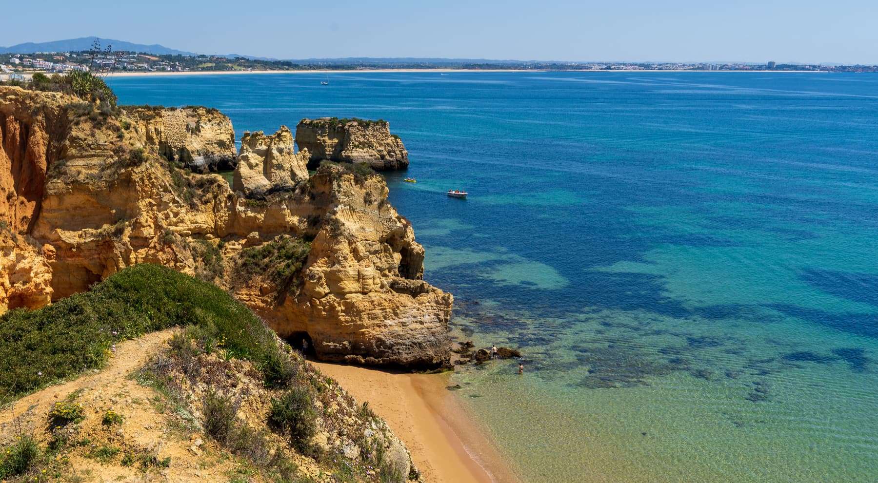 Golden sandstone cliffs, a small cove beach and turquoise water on the Algarve coast