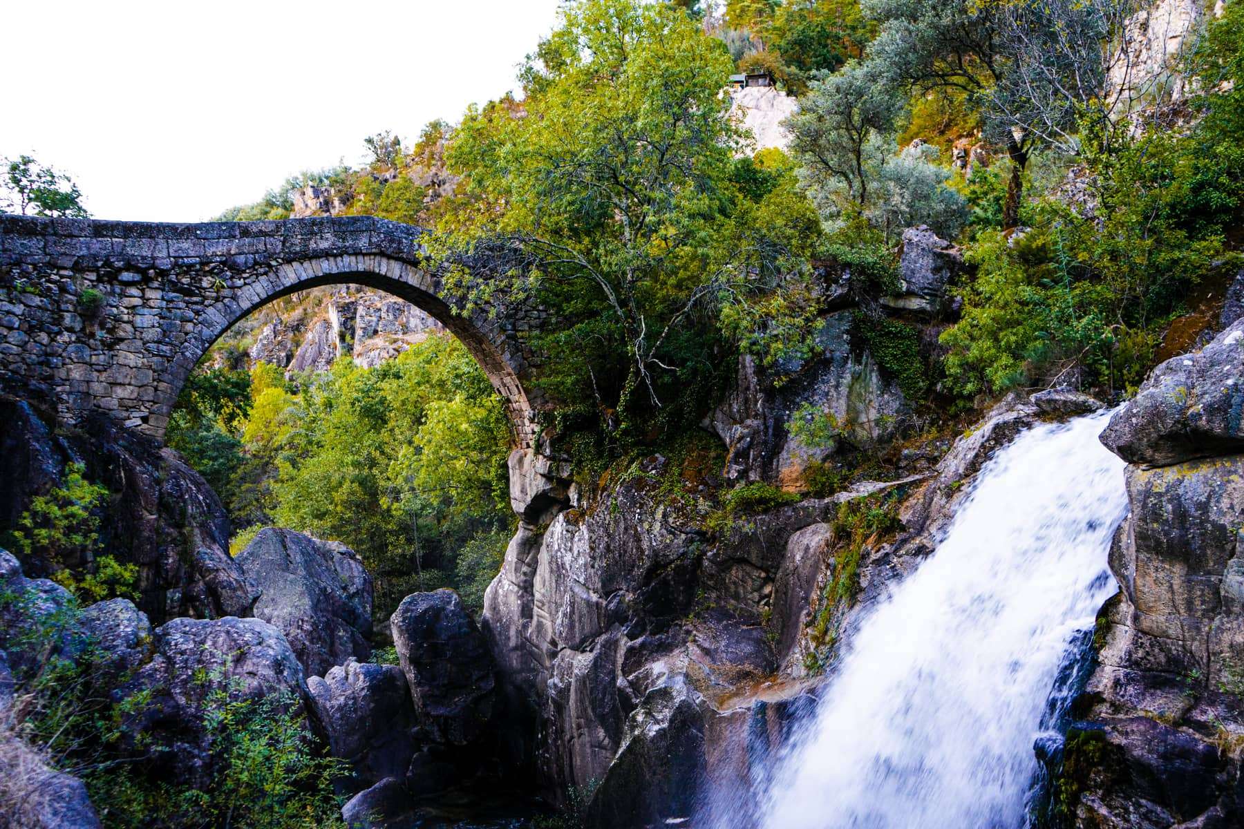 An old stone arch bridge beside a waterfall in the Peneda-Gerês mountains